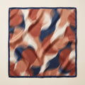 Square satin scarf with abstract rust, terracotta, cream and navy print and navy border laid flat