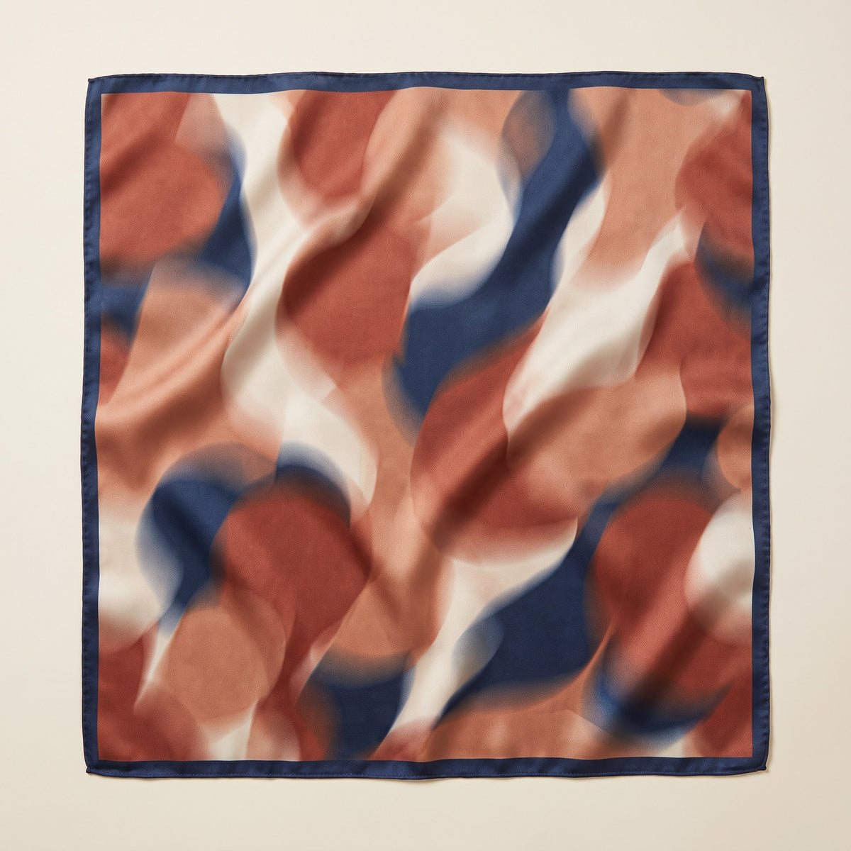 Square satin scarf with abstract rust, terracotta, cream and navy print and navy border laid flat