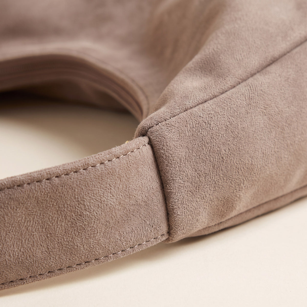Close-up of the brushed faux suede and stitched strap join on the taupe hobo bag