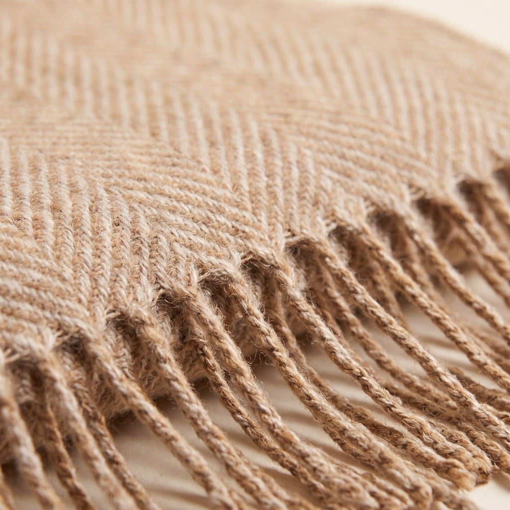 Close-up of the camel and oatmeal herringbone weave and twisted fringe of the oversized scarf