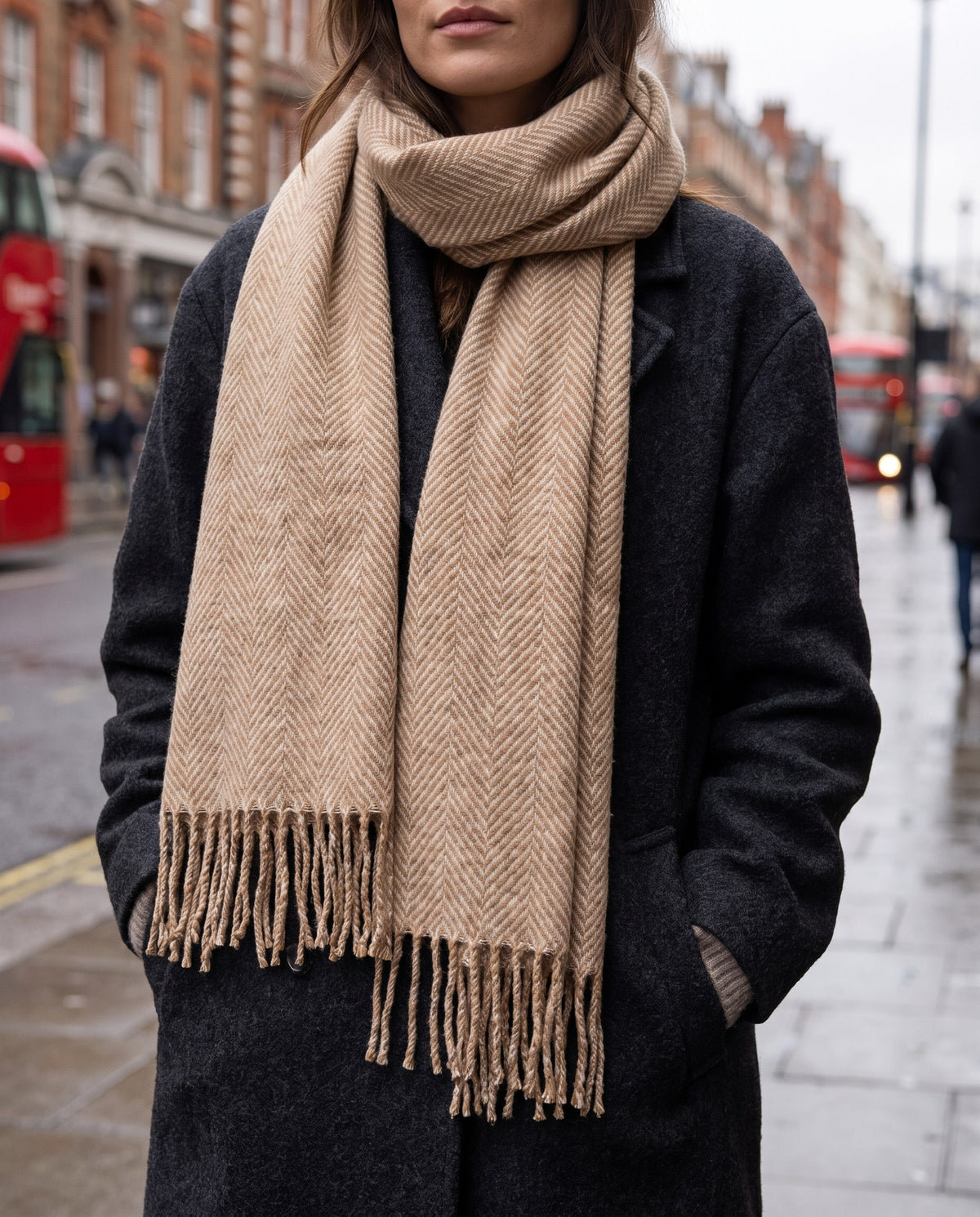 Woman in a charcoal coat wearing the camel herringbone scarf on a London street