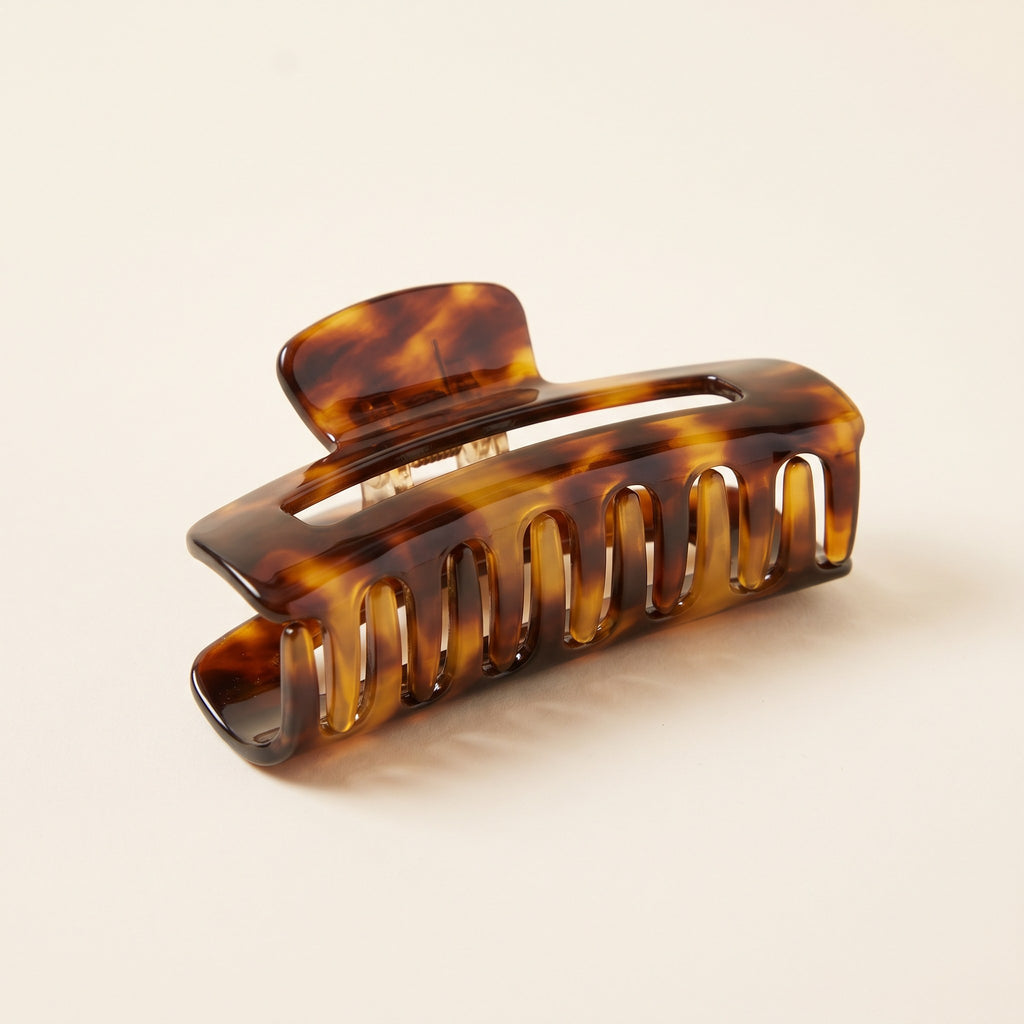Large Tortoiseshell Claw Clip in glossy amber and brown acetate on an ivory background