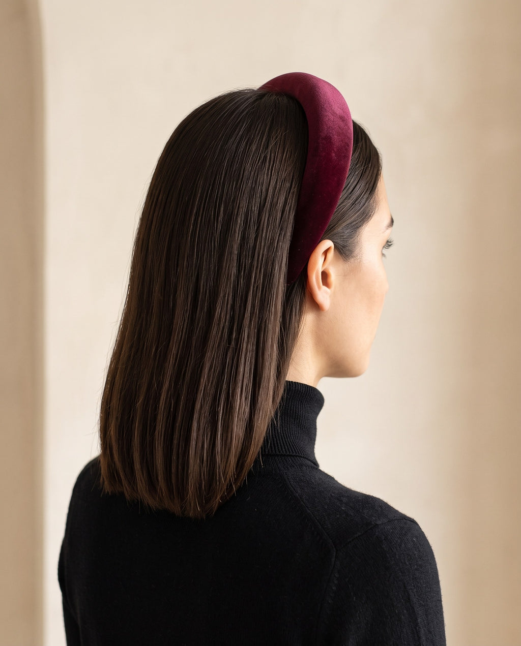 Woman with sleek dark hair wearing the burgundy padded velvet headband, seen from the side