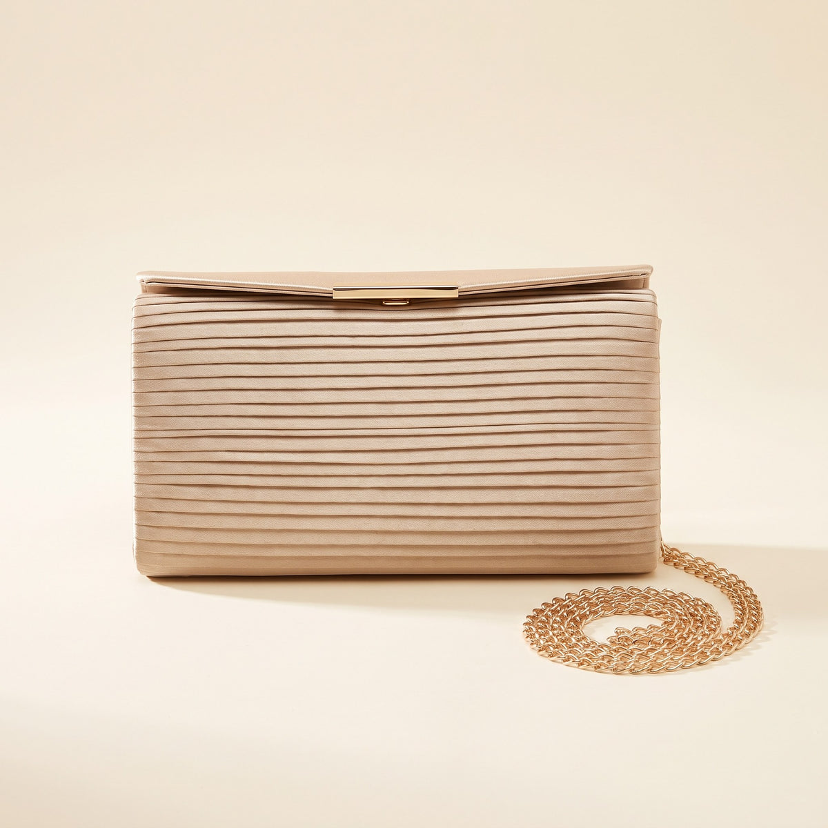 Pleated Satin Evening Clutch in champagne with gold-tone bar clasp and chain strap on an ivory background