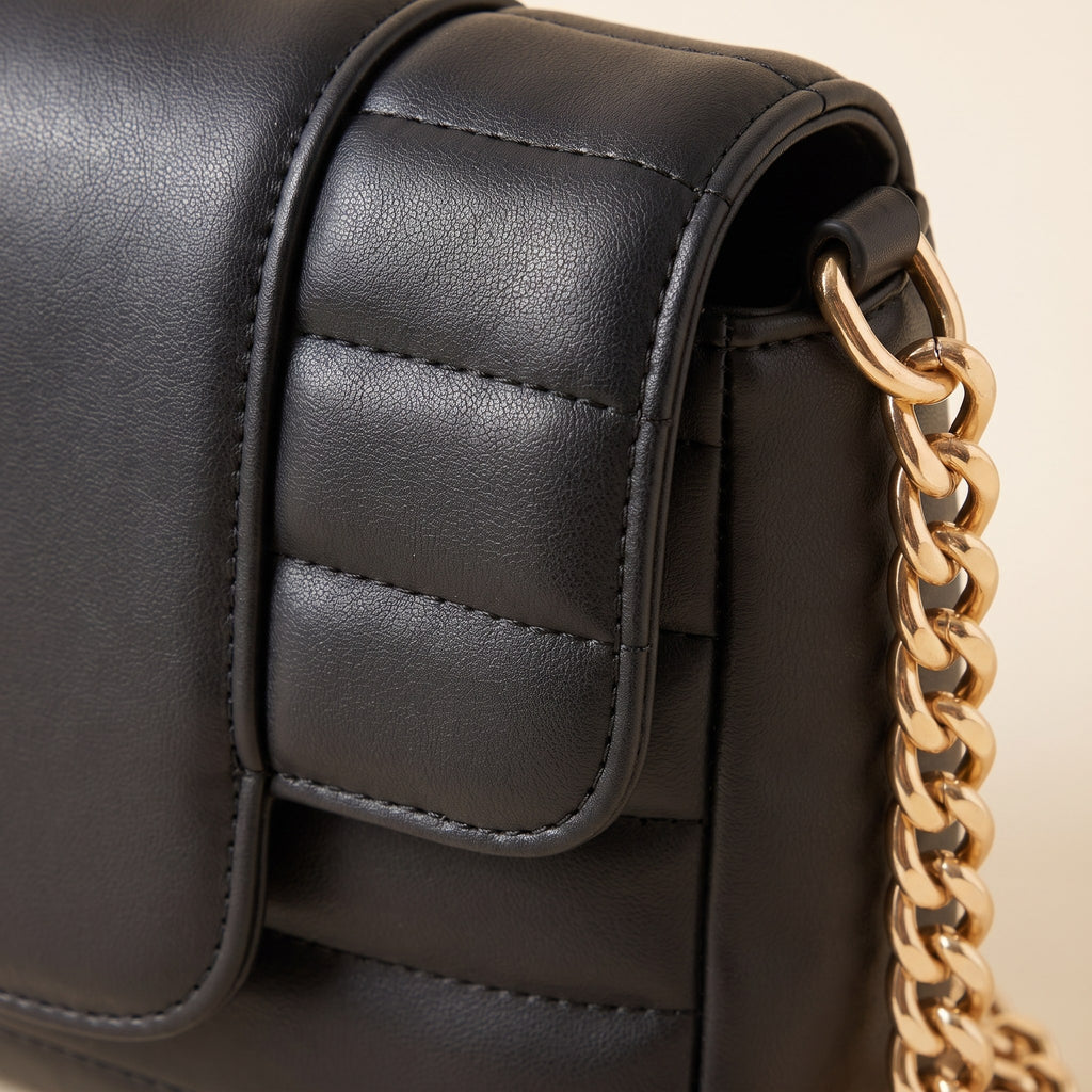 Close-up of the channel quilting and gold-tone curb chain on the black crossbody bag