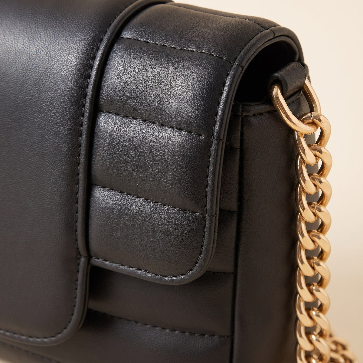 Close-up of the channel quilting and gold-tone curb chain on the black crossbody bag