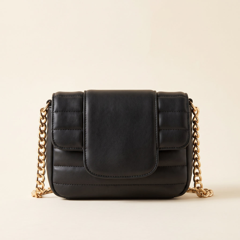 Quilted Chain Crossbody Bag in black channel-quilted faux leather with a chunky gold-tone chain strap on an ivory background