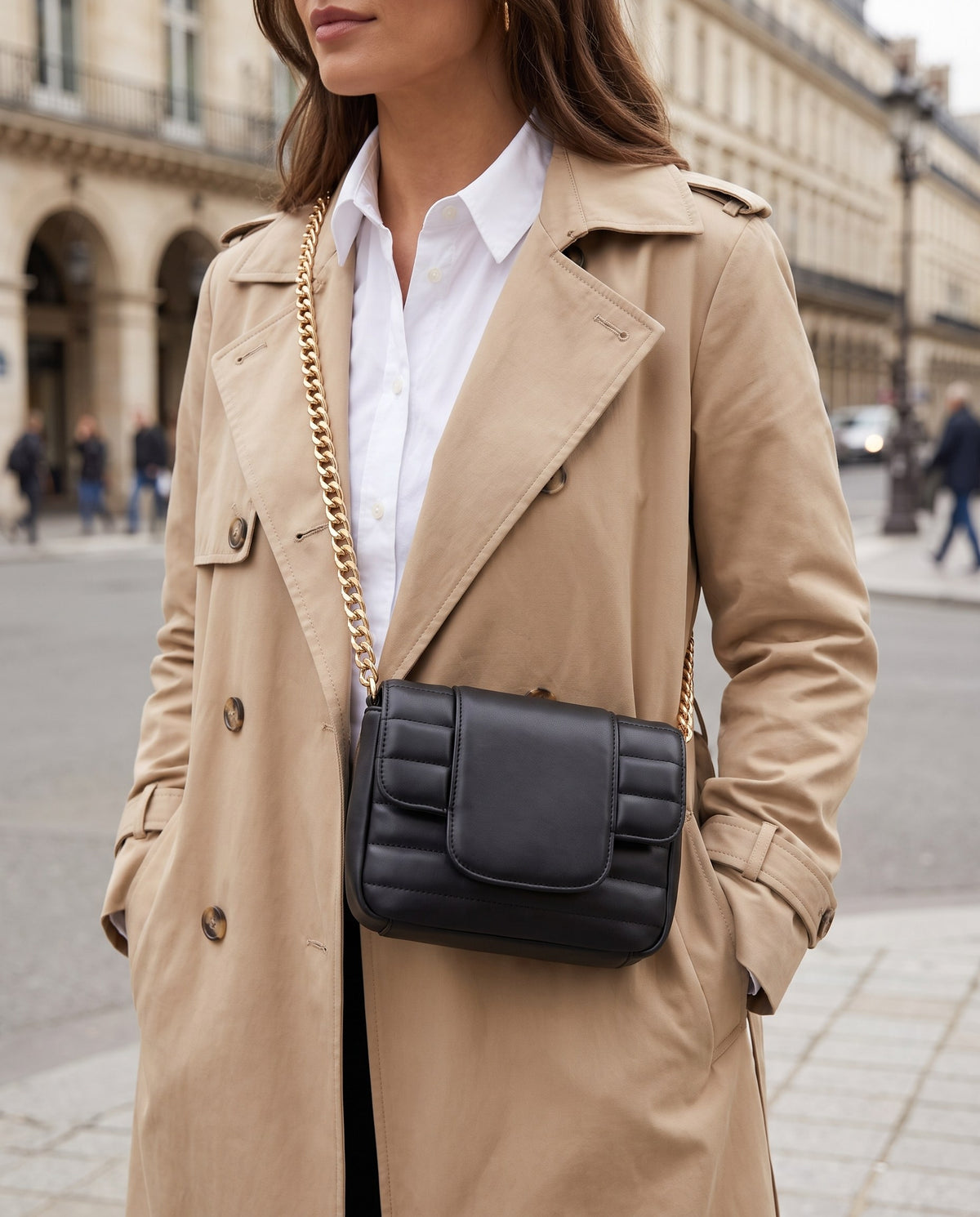 Woman in a beige trench coat wearing the black Quilted Chain Crossbody Bag across her body